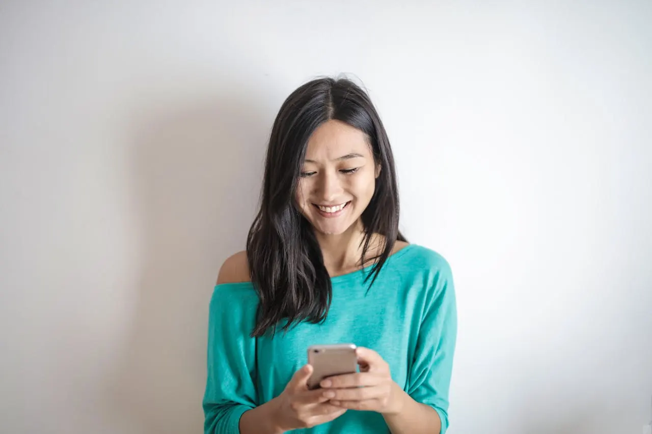 A parent smiling while using their phone